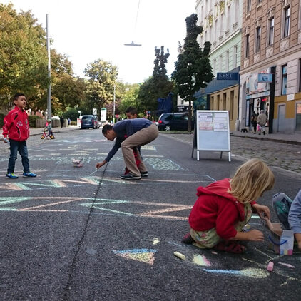 Kinder und Erwachsene malen mit Kreiden auf der Straße